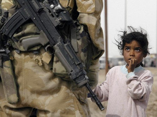 2003年3月27日,在伊拉克巴士拉城外,一名伊拉克女孩惊恐地注视背枪的